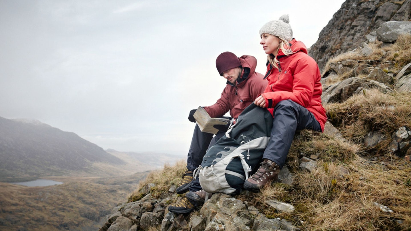 Hikers sitting on a rock, one looks at the view another consults the map