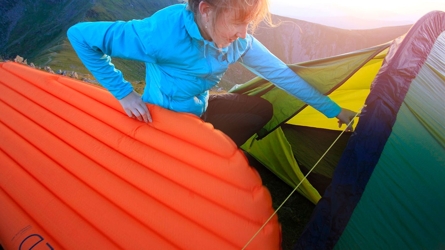 Woman putting a sleeping mat into a tent