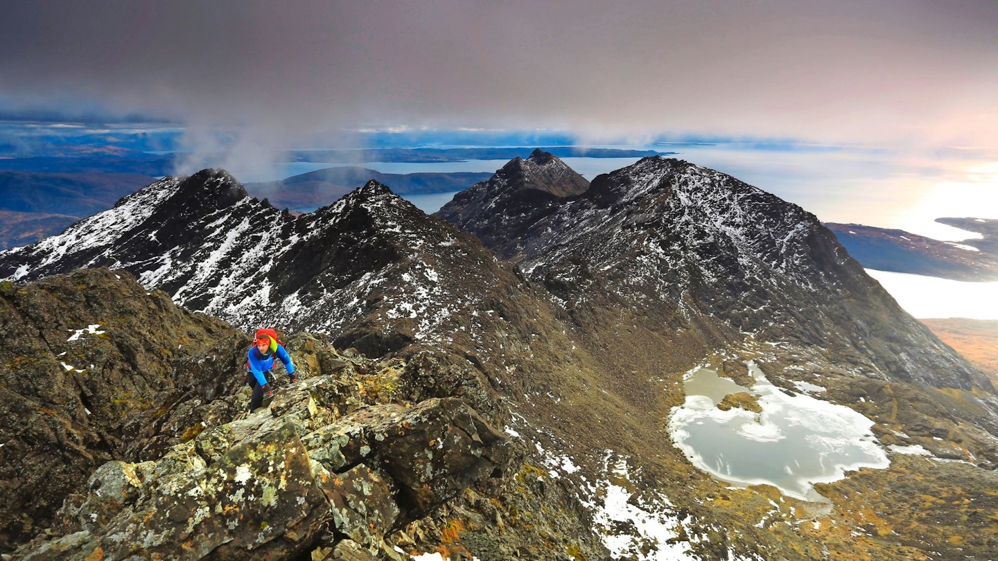 Hiker climbing along Sgurr Alasdair with Loch Coire below