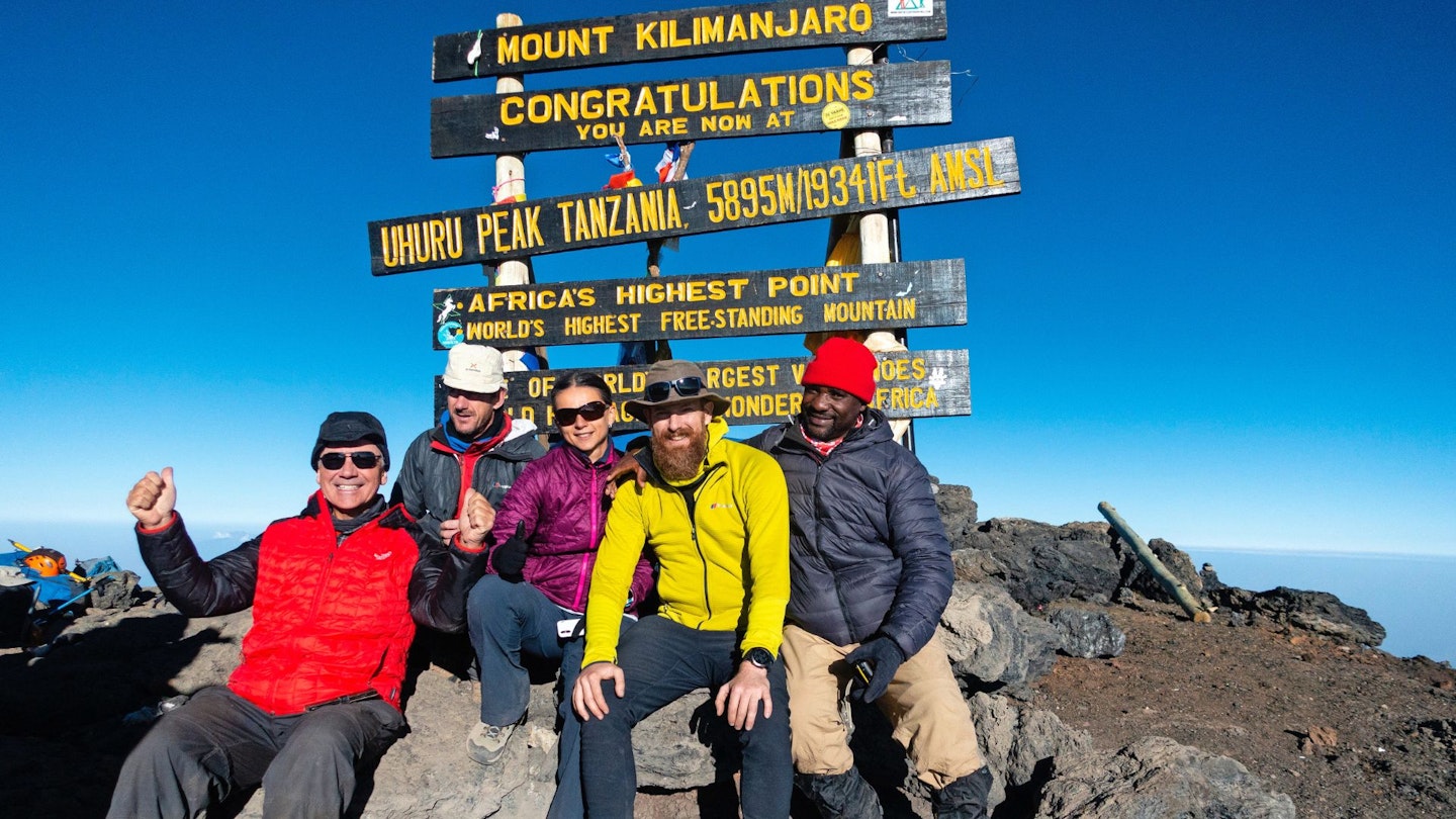 Writer Ben Weeks sits on the summit of Kilimanjaro